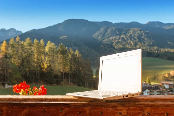 A laptop on a wooden table in a country house in autumn mountains