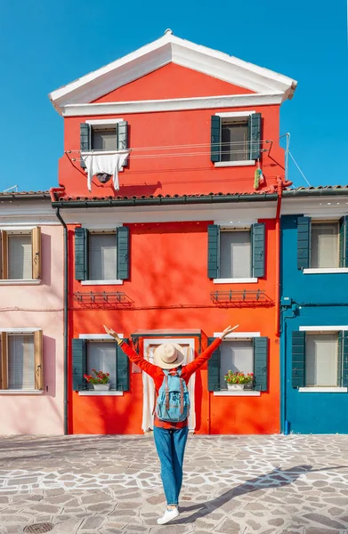 young happy traveler woman posing among colorful houses on Burano island, Venice. Tourism in Italy concept
