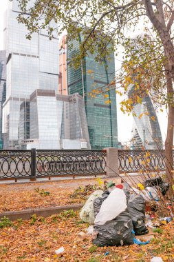 Kentsel çevre sosyal sorunlar. Bir sürü şehir merkezinde modern gökdelenler arka plan üzerinde parkta bir depolama çeşitli çöpe