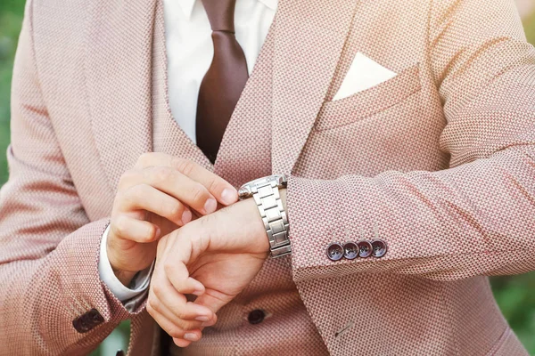 Styled man in vintage suit looking at his luxury wristwatch