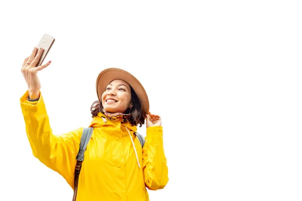 Азіатські жінки, беручи selfie в жовтий пальто і капелюх, ізольовані на білому. Подорож в осінній сезон концепції — стокове фото