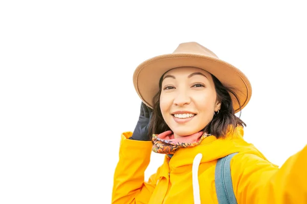 Азіатські жінки, беручи selfie в жовтий пальто і капелюх, ізольовані на білому. Подорож в осінній сезон концепції — стокове фото