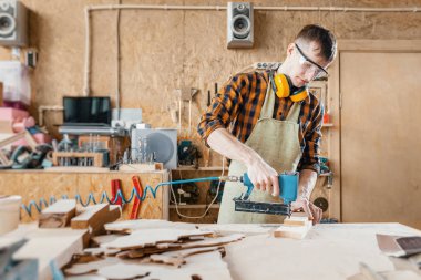 Marangoz atölyesinde çivi tabancası taç ahşap panoları kullanarak. MKK