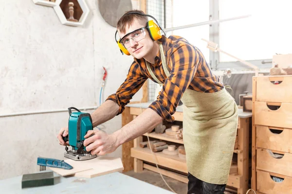Man carpenter with jigsaw working in professional workshop — Stock Photo, Image