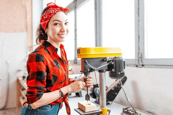 A strong and independent Asian woman works on a drilling machine — Stock Photo, Image