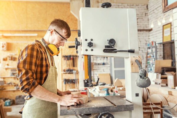 Professional carpenter man working on a machine with a wooden wo