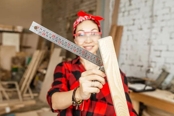 Donna professionista lavora con il legno e lo misura con un righello — Foto Stock