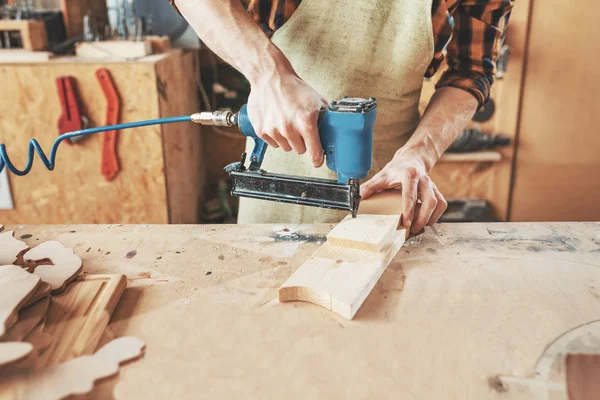 Timmerman met behulp van nagel pistool aan kroon houten planken in de werkplaats. CRA — Stockfoto