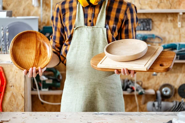 Carpintero profesional sostiene en la mano un plato hecho a mano acabado de — Foto de Stock