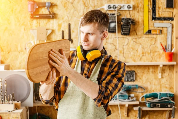 Man carpenter holding a finished product made of wood - cutting — Stock Photo, Image