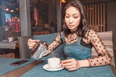 Bir kadın bir restoranda bir su ısıtıcısı çay döker