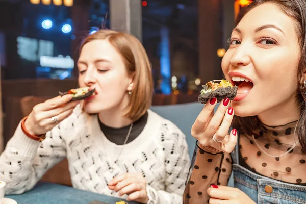 Dos chicas amigas charlan y ríen en el restaurante y comen tapas españolas. Concepto de amistad y relaciones — Foto de Stock