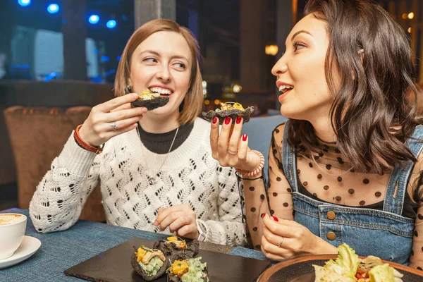 Twee vriendin meisjes chatten en lachen in het restaurant en eten Spaanse tapas. Concept van vriendschap en relaties — Stockfoto