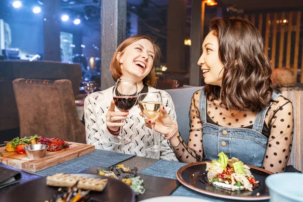 Two girls friends chatting and drinking wine in a restaurant in a nightclub. Concept of friendship and food and drinks