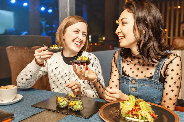 Dvě dívky si popovídejte a smějí se v restauraci a jedí španělské tapas. Koncepce přátelství a vztahů — Stock fotografie