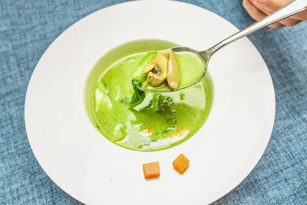 Man med en sked grön grädde soppa och tallrik i restaurangen. Begreppet hälsosam mat och vegetarisk kost — Stockfoto