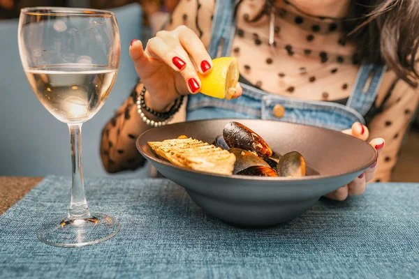 Mujer comiendo deliciosos mejillones cocinados chef con limón y vino blanco en el restaurante —  Fotos de Stock