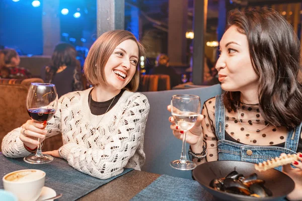 Dvě kamarádky si užijí a baví se, když popíjejí sklenku vína v restauraci v nočním klubu. Koncept relaxační a vlenské lodi — Stock fotografie