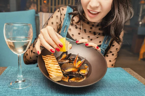 Woman eating delicious chef cooked mussels with lemon and white wine in restaurant — Stock Photo, Image