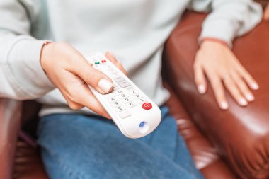 Kız kanepede oturur ve uzaktan kumanda ile Tv kanalları anahtarları. Film ve haber izleme kavramı