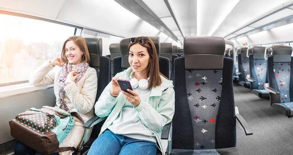 İki kız arkadaşı kız metroda trene binmek ve cep telefonlarını kullanmak — Stok fotoğraf