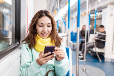 Asyalı kadın metro trende akıllı telefon kullanarak