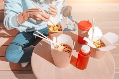 Moda asya genç hipster kız çubukları ile Oriental wok erişte yiyor. Kağıttan yapılan öğle yemeği ve doğal paket kaplar konsepti