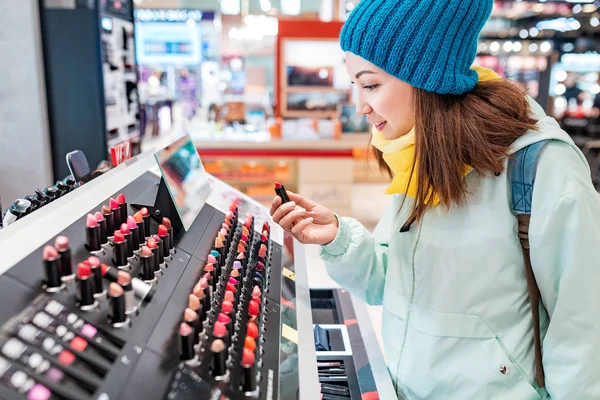 Nő vásárol rúzs és egyéb kozmetikumok egy boltban — Stock Fotó