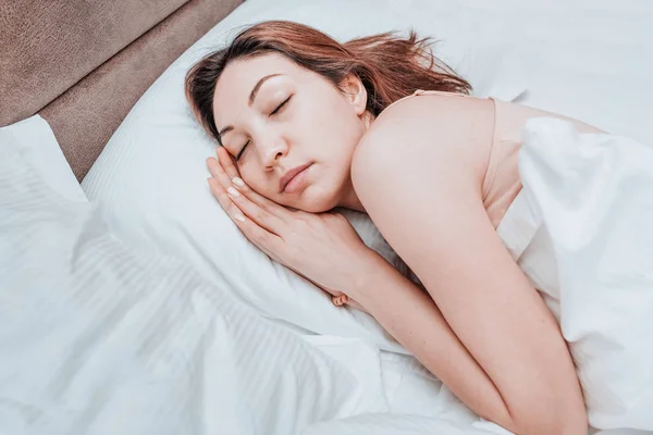 Asian woman sleeps relaxed on a large spacious bed at home or in a hotel