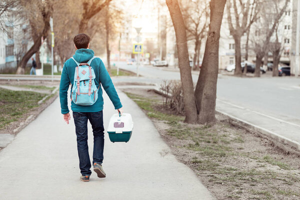 Man with domestic cat in a pet carrier traveling on the street