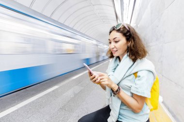 Onu treni beklerken Asya kadın Metro akıllı telefon kullanır. Mobil cihazlar için taşıma uygulaması kavramı