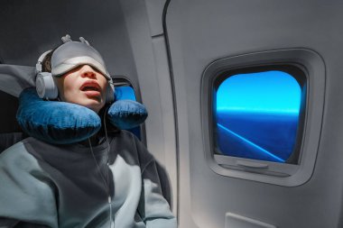 Asian girl sleeping in her seat on the plane near the window in  clipart