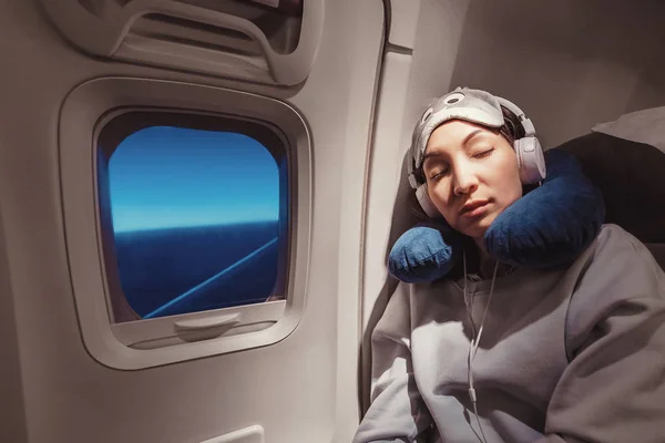 Asiatische Mädchen schlafen in ihrem Sitz im Flugzeug in der Nähe des Fensters in — Stockfoto