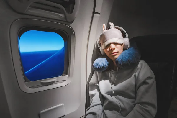 Menina asiática dormindo em seu assento no avião perto da janela em — Fotografia de Stock