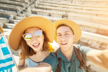 Avrupa adam ve aşk Asyalı kız bir çift turist bir bayrak ile eski bir Yunan Akropol bir selfie almak. Yunanistan 'da seyahat ve macera