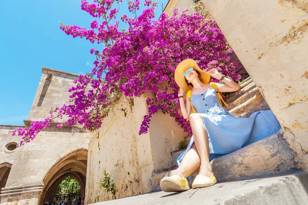 Elegantní žena v klobouku, která se chová blízko kvetoucích fialových květin — Stock fotografie