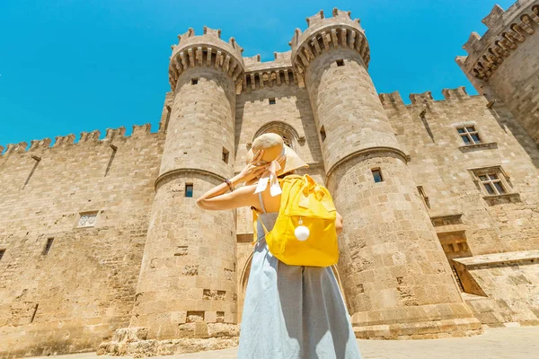 Happy Ασιατική γυναίκα ταξιδιώτη απολαμβάνοντας την υπέροχη θέα στο παλιό κάστρο των Ιπποτών Μέγας Μάστερ στη Ρόδο, Ελλάδα — Φωτογραφία Αρχείου