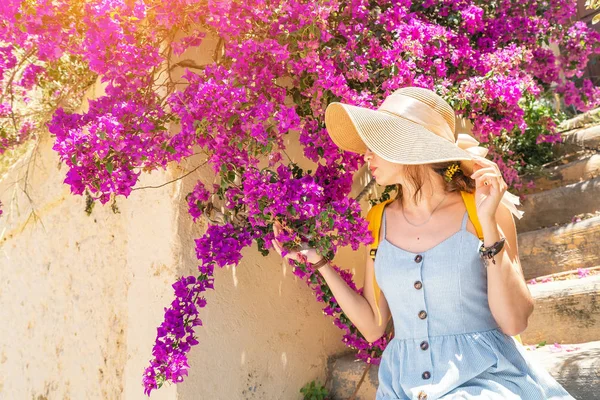 Elegante donna in cappello posa vicino fioritura fiori viola — Foto Stock