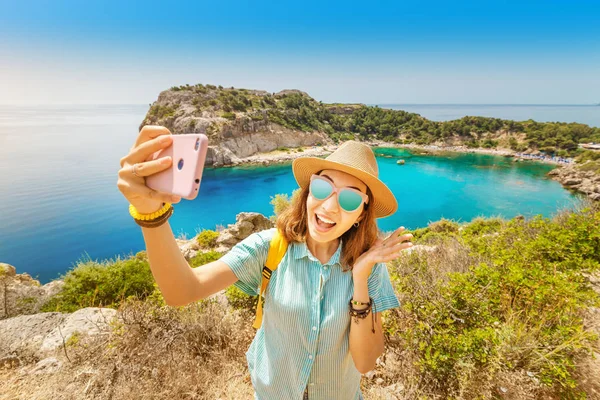 Ázsiai lány egy kalapban vesz egy selfie a háttérben a lenyűgöző kilátás nyílik az azúrkék-öböl a Földközi-tengeren. Utazás, vakáció és mobil csatlakozási koncepció — Stock Fotó