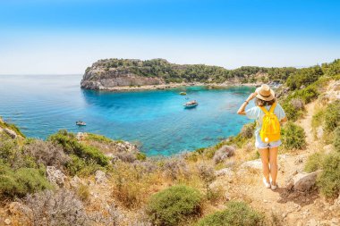 Tropik bir tatil beldesinde güzel bir masmavi Koy hayran sarı bir sırt çantası ile yalnız bir kızın arka görünümü