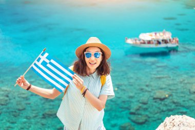 Akdeniz'in güzel Körfezi'nde cruise tekneleri arka planda Yunan bayrağı ile Mutlu kız. Yunanistan'da seyahat ve su taşımacılığı konsepti
