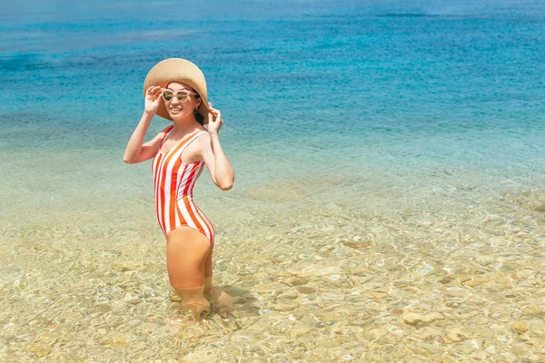 Atraktivní asijská žena v uzavřeném proužku se nachází na pláži letoviska na pobřeží klidného azurového moře — Stock fotografie