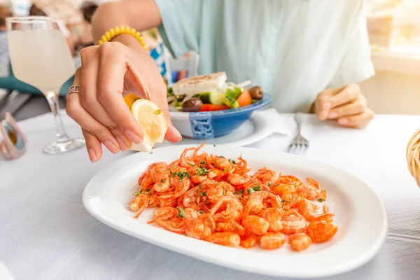 Girl in the restaurant eats delicious little shrimps and prawns from Symi island, Greece. Seafood and mediterranean cuisine concept — Stock Photo, Image