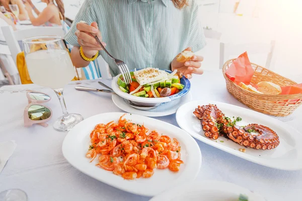 Close-up of a woman eating delicious seafood - shrimp and octopus grilled and vegetable salad. The concept of Mediterranean cuisine and healthy food — Stock Photo, Image