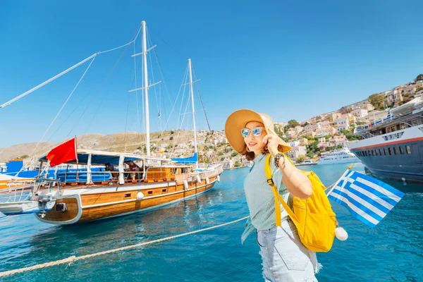 Šťastná žena s řeckou vlajkou nedaleko výletních lodí. Koncepce námořní dovolené a cestování — Stock fotografie