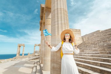 Antik Yunan harabelerinde Yunan bayrağı taşıyan genç bir gezgin kadın. Yunanistan 'da turizm kavramı