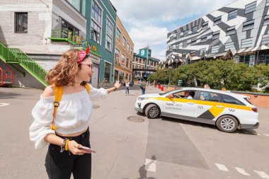 01 June 2019, Moscow, Russia: Woman catching yandex taxi with a gesture clipart
