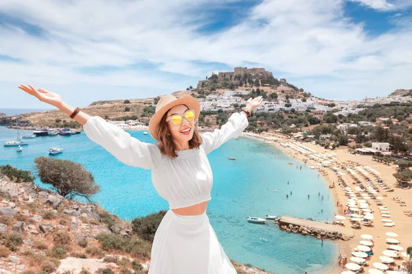 Glückliche asiatische Frau hob die Hände Reisen in Griechenland. Spaß am atemberaubenden Blick auf den Badeort und die Altstadt von Lindos auf dem Berg — Stockfoto