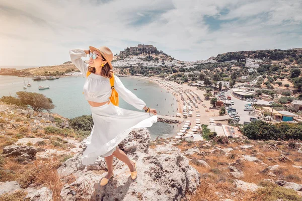 Šťastná asijská žena cestuje v Řecku. Zábava v úžasném pohledu na mořské letovisko a staré město Lindos na hoře — Stock fotografie