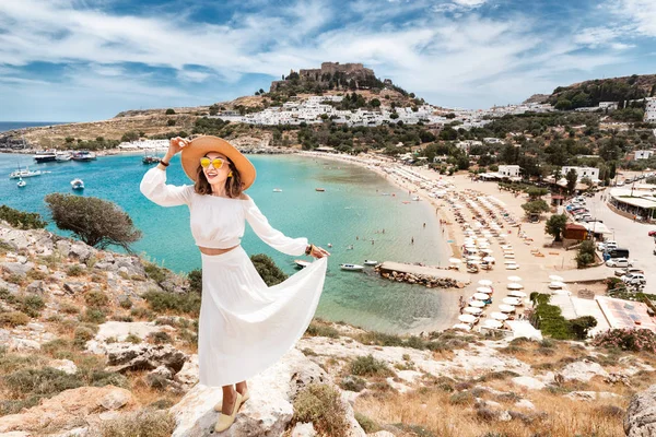 Glückliche asiatische Frau reist in Griechenland. Spaß am atemberaubenden Blick auf den Badeort und die Altstadt von Lindos auf dem Berg — Stockfoto